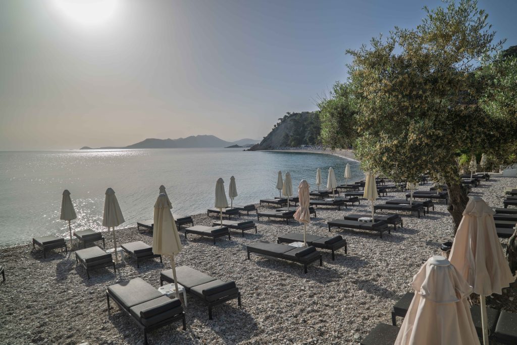 Sonnenliegen und türkisfarbenes Wasser an der Navagos Beach Bar auf Samos.